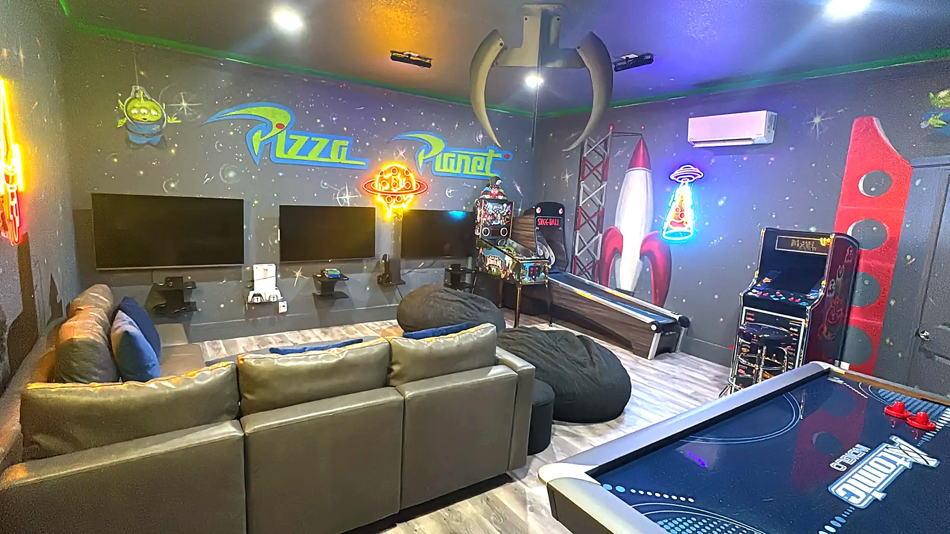 Pizza Planet themed game room with air hockey, arcade, pinball, and skee-ball