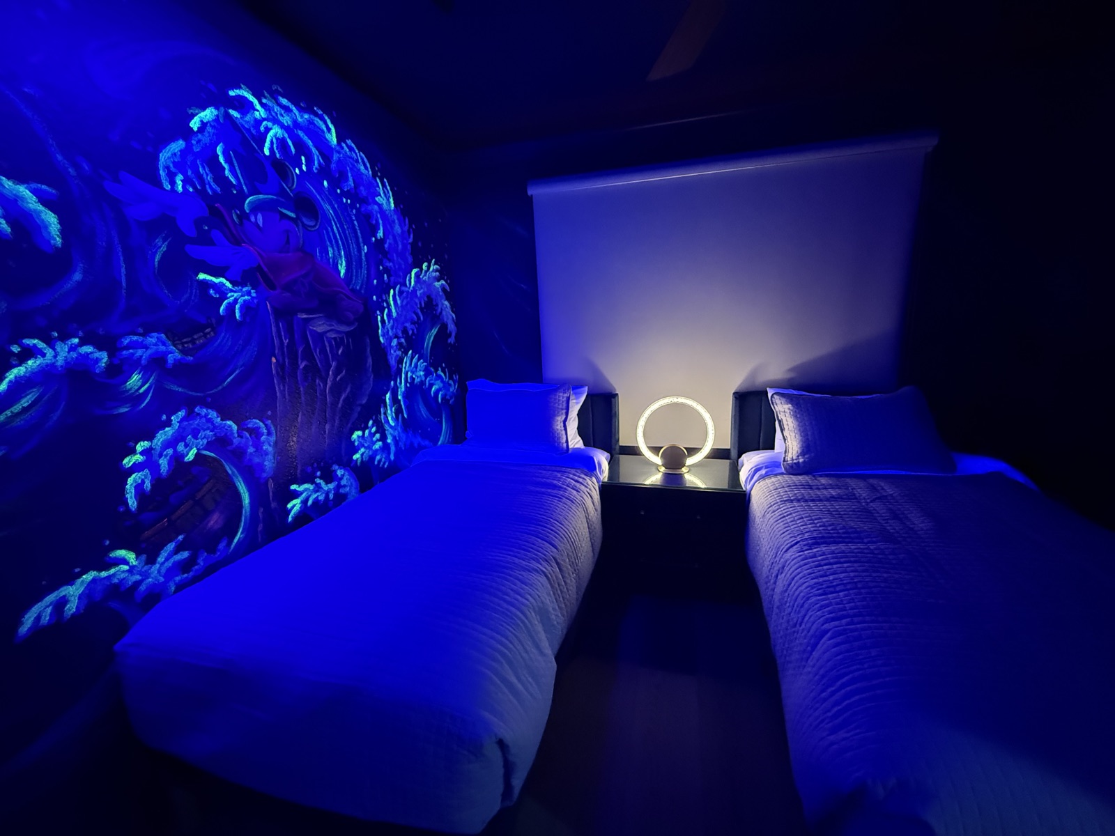 Fantasia Sorcerer Mickey twin bedroom with the wave mural glowing under blacklight