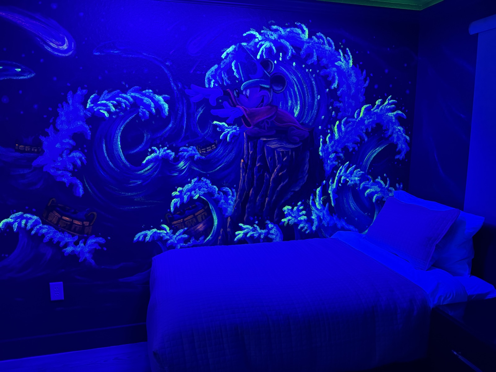 Glowing Sorcerer Mickey wave mural under blacklight in the Fantasia bedroom
