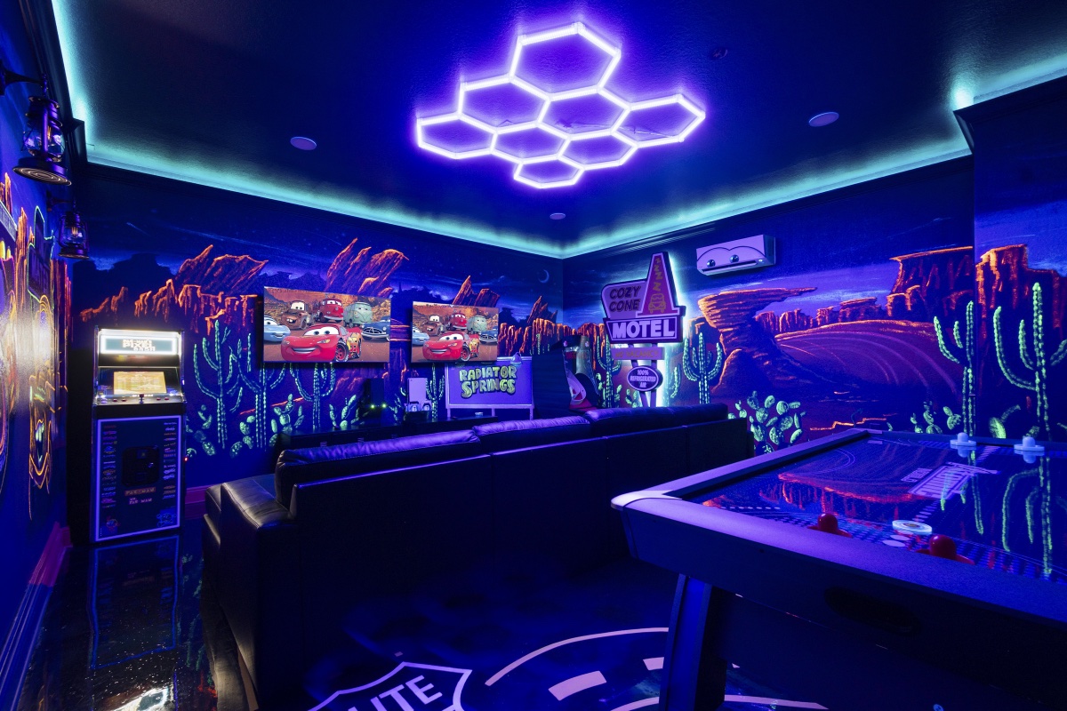 Cozy Cone Motel mural glowing under blacklight with Pac-Man arcade and air hockey