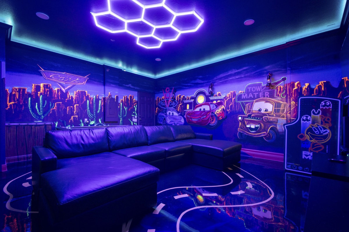 Sectional sofa and Route 66 floor glowing under blacklight in the Radiator Springs game room