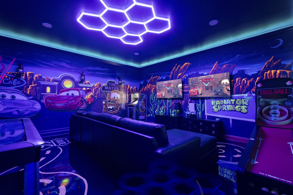 Skee-ball and Route 66 floor glowing under blacklight in the Radiator Springs game room