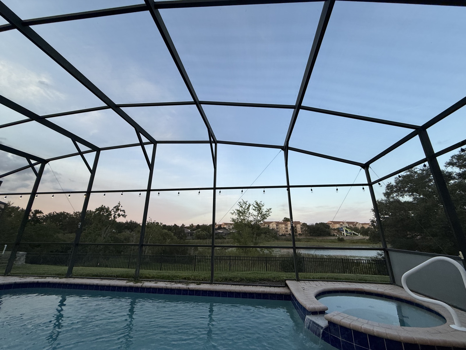 Screened pool and spa at sunset with lake views at Time-Out Corner, Lakeside