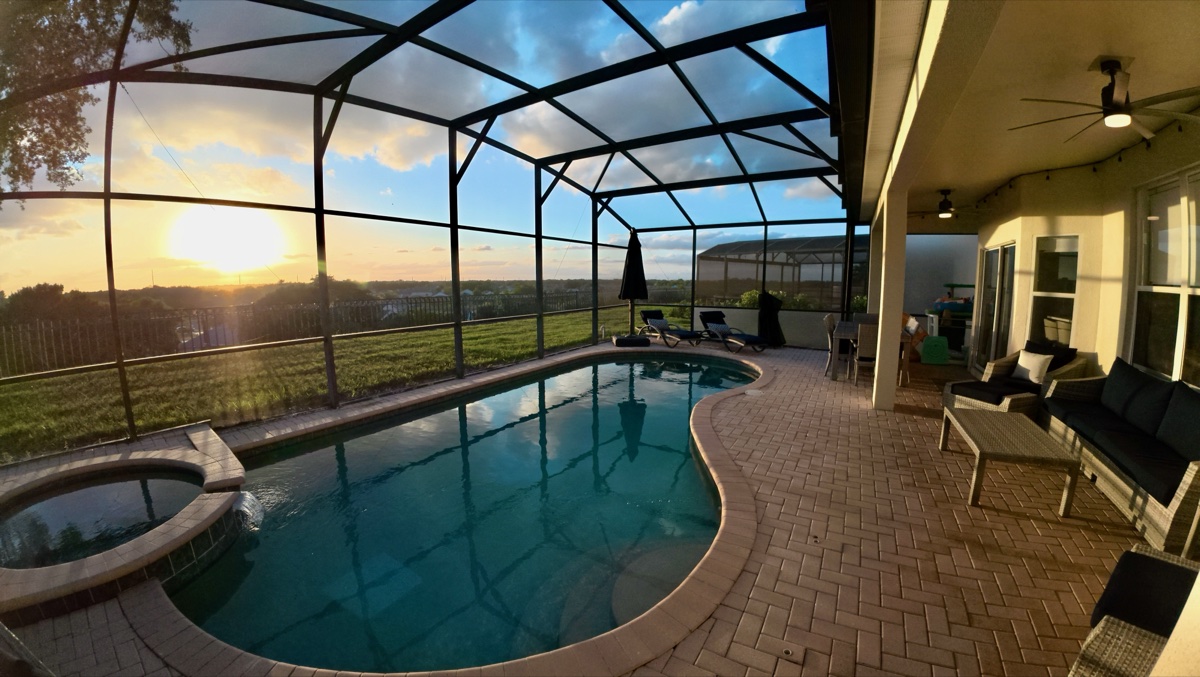 Sunset behind the pool with lanai seating in the foreground