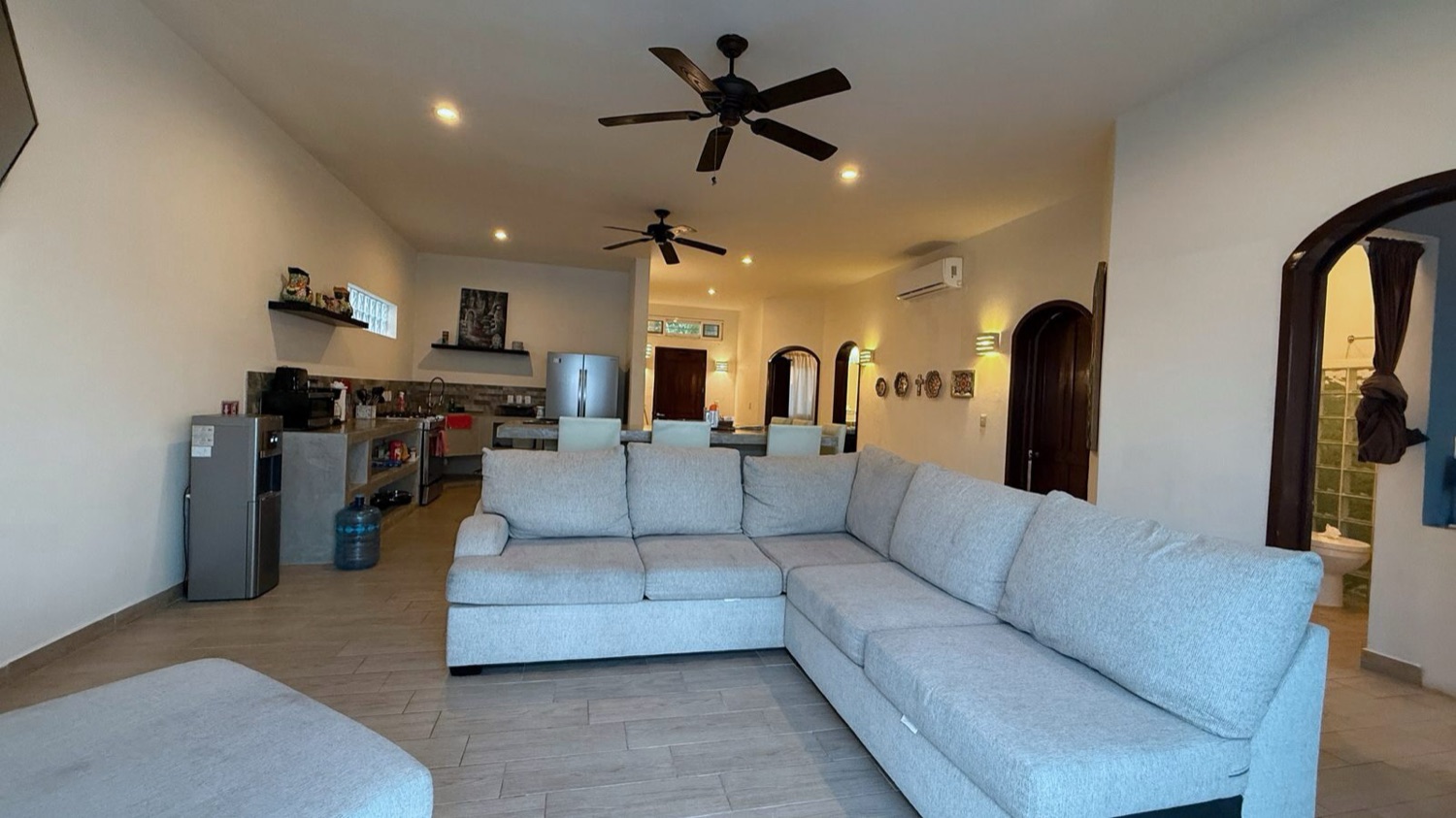 Open-plan living room with white sectional and ocean light at Rincón del Descanso, Isla Mujeres